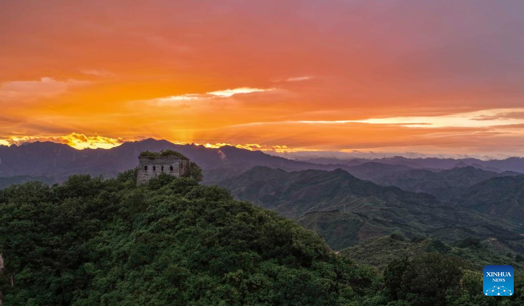Céu avermelhado ao pôr do sol realça a imponência da Grande Muralha em Hebei, norte da China
