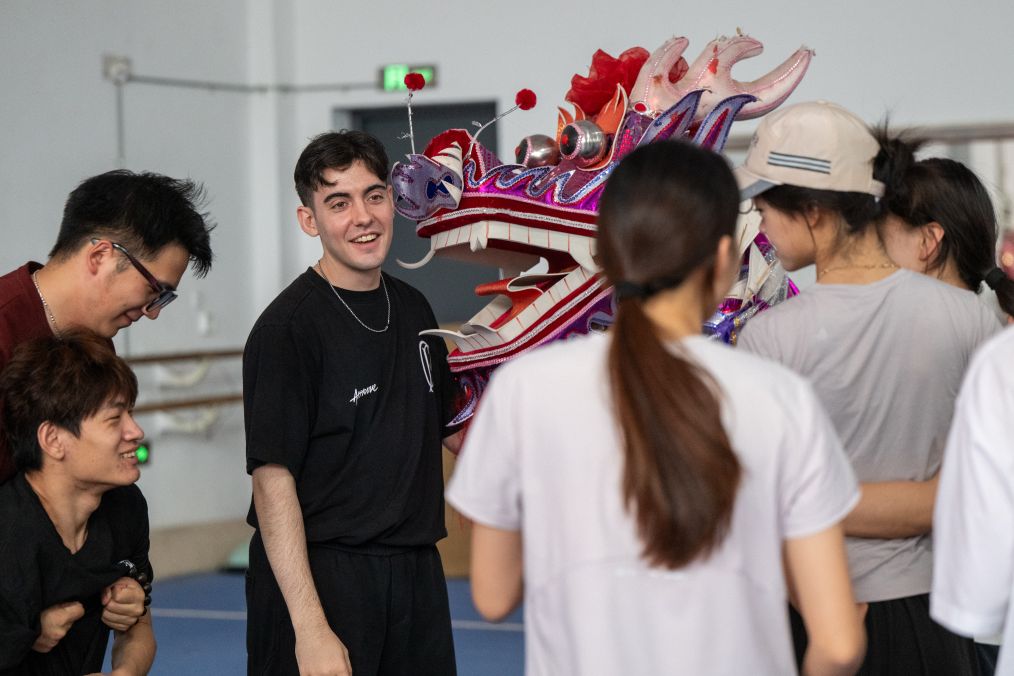 Manacero (3º à Esquerda) treina membros da equipe de dança do dragão em um ginásio da Universidade de Hubei em Wuhan, na Província de Hubei, centro da China, em 18 de junho de 2026. (Xinhua/Du Zixuan)